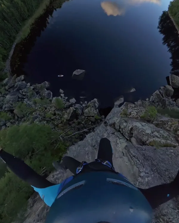 Vista en primera persona de un salto BASE sobre un lago de montaña